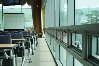 Empty seminar room with desks and chairs along a row of windows