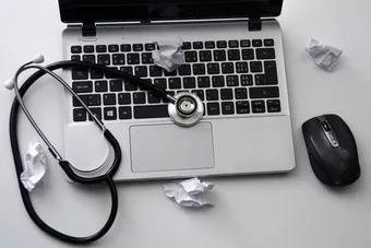 Laptop with a stethoscope and crumpled balls of paper