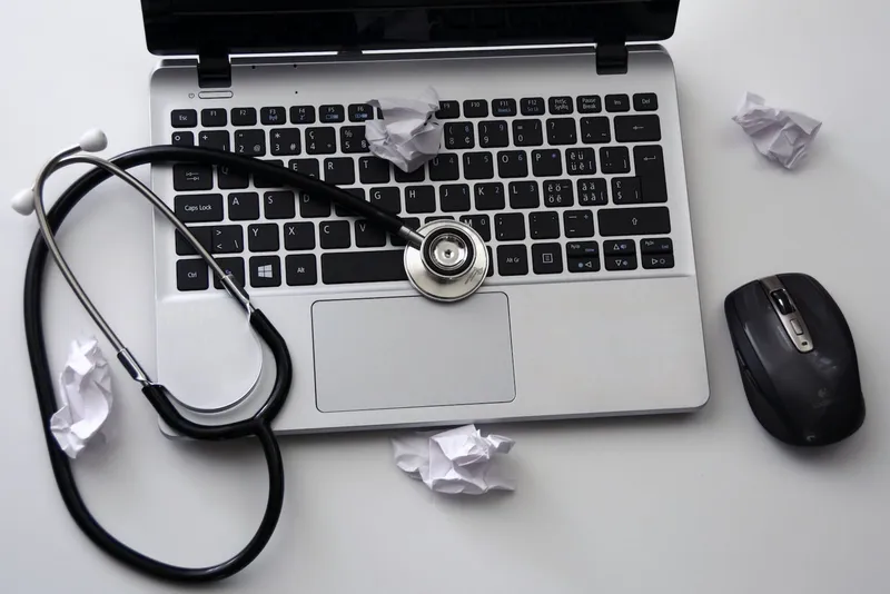 Laptop with a stethoscope and crumpled balls of paper